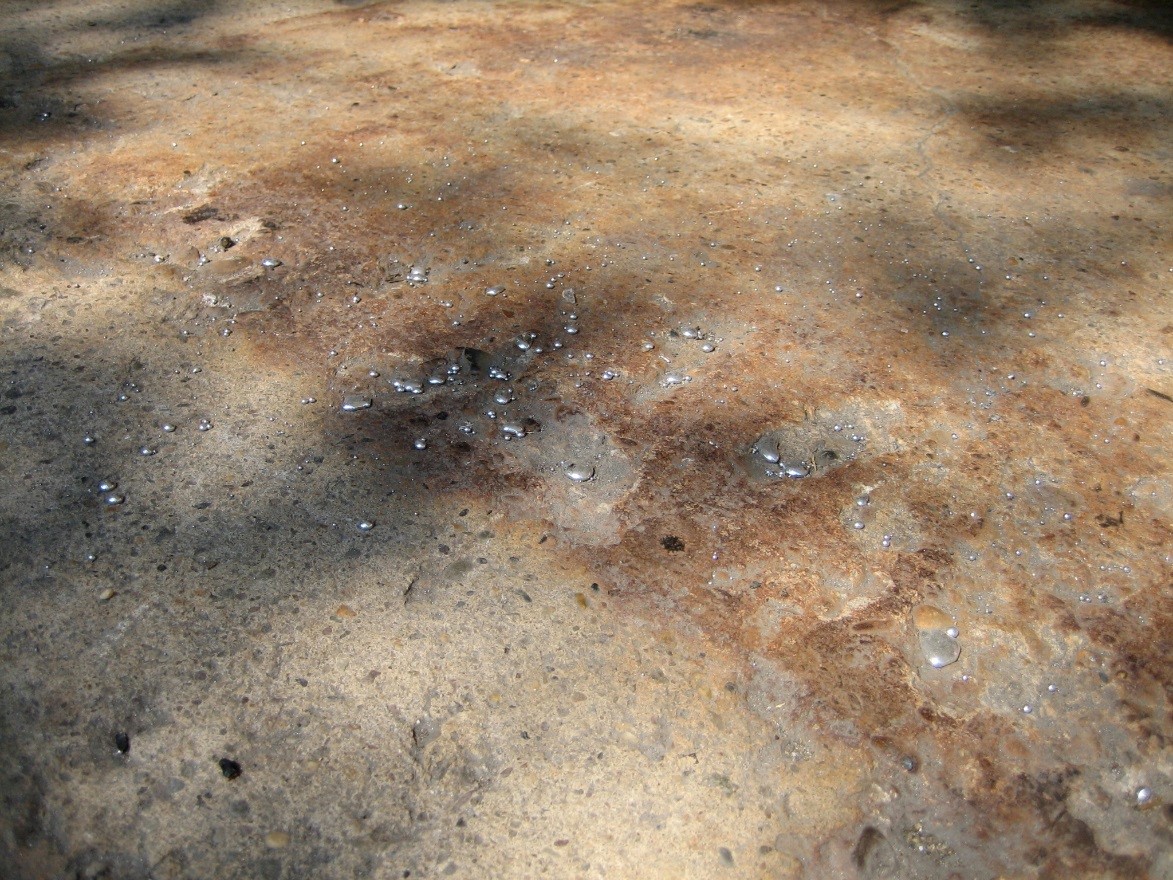 Large drops of liquid mercury scattered across floor